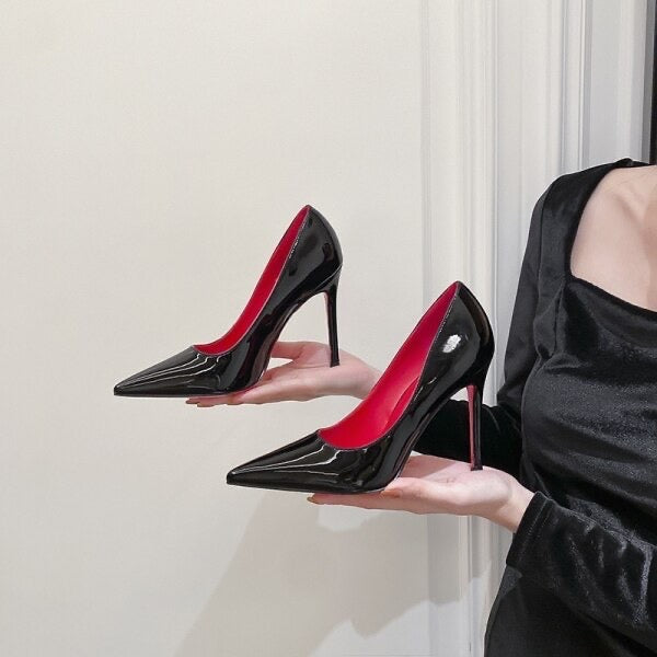 Black high heeled court shoe with red sole