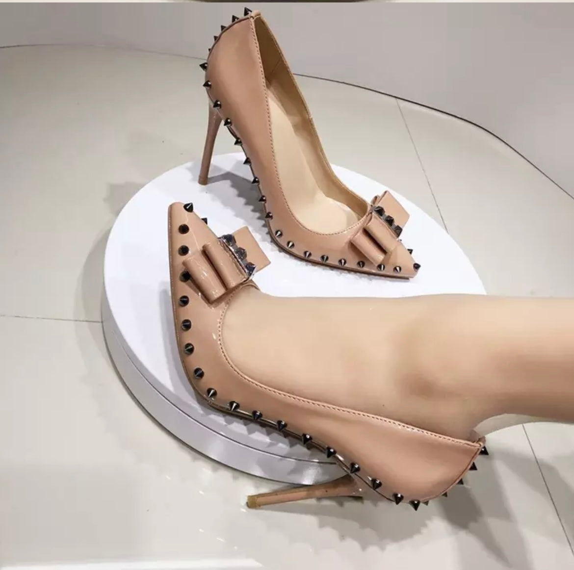 Nude high heeled court shoe with spikes and a bow